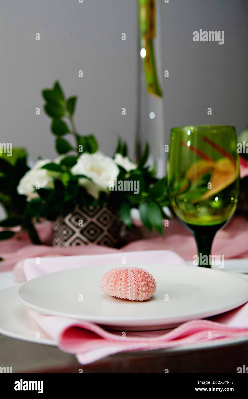 Zarte Tischeinrichtung mit rosafarbenen Elementen und Muscheldetails Stockfoto