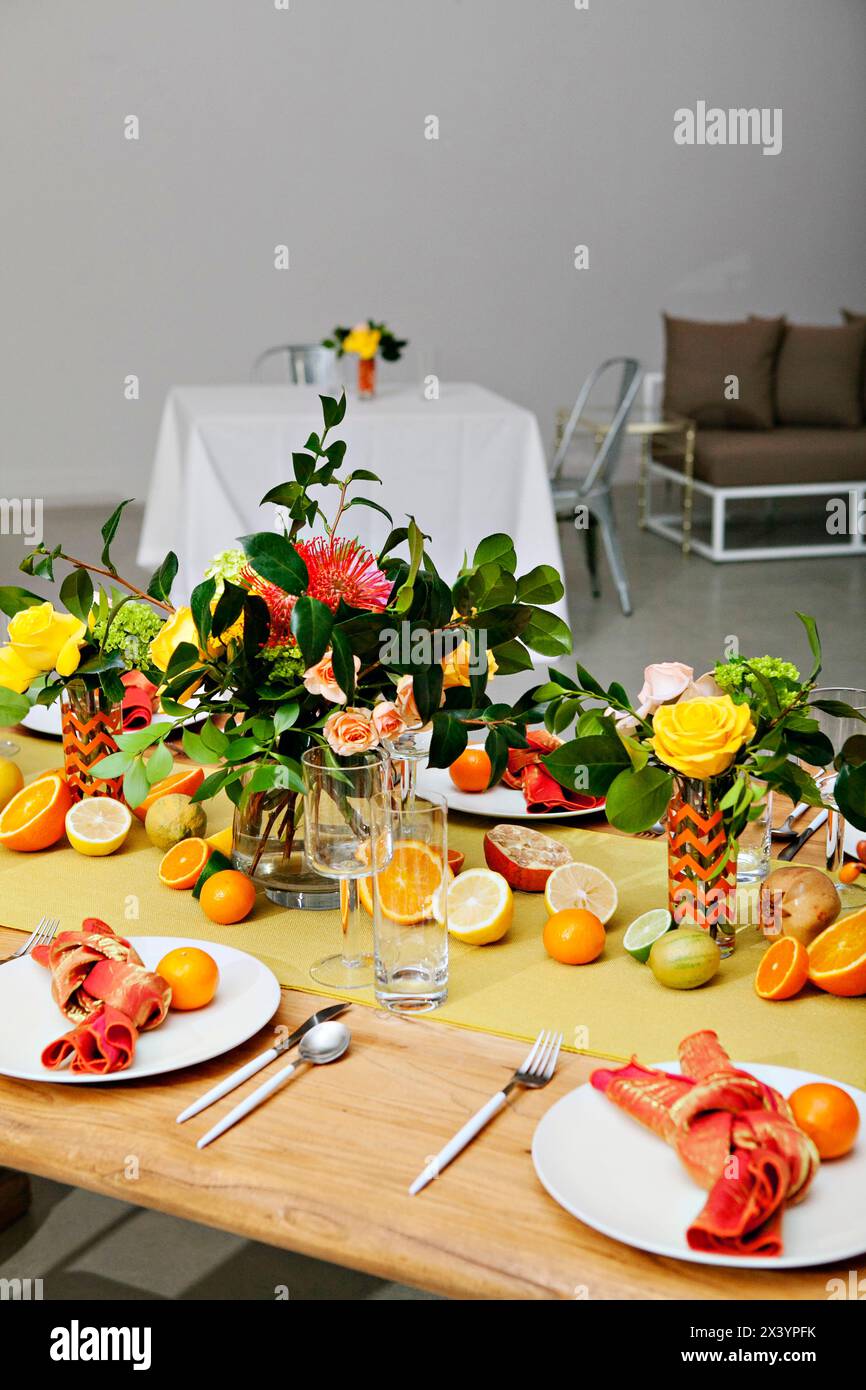 Farbenfroher Esstisch mit frischen Zitrusfrüchten und Blumenmotiven. Stockfoto