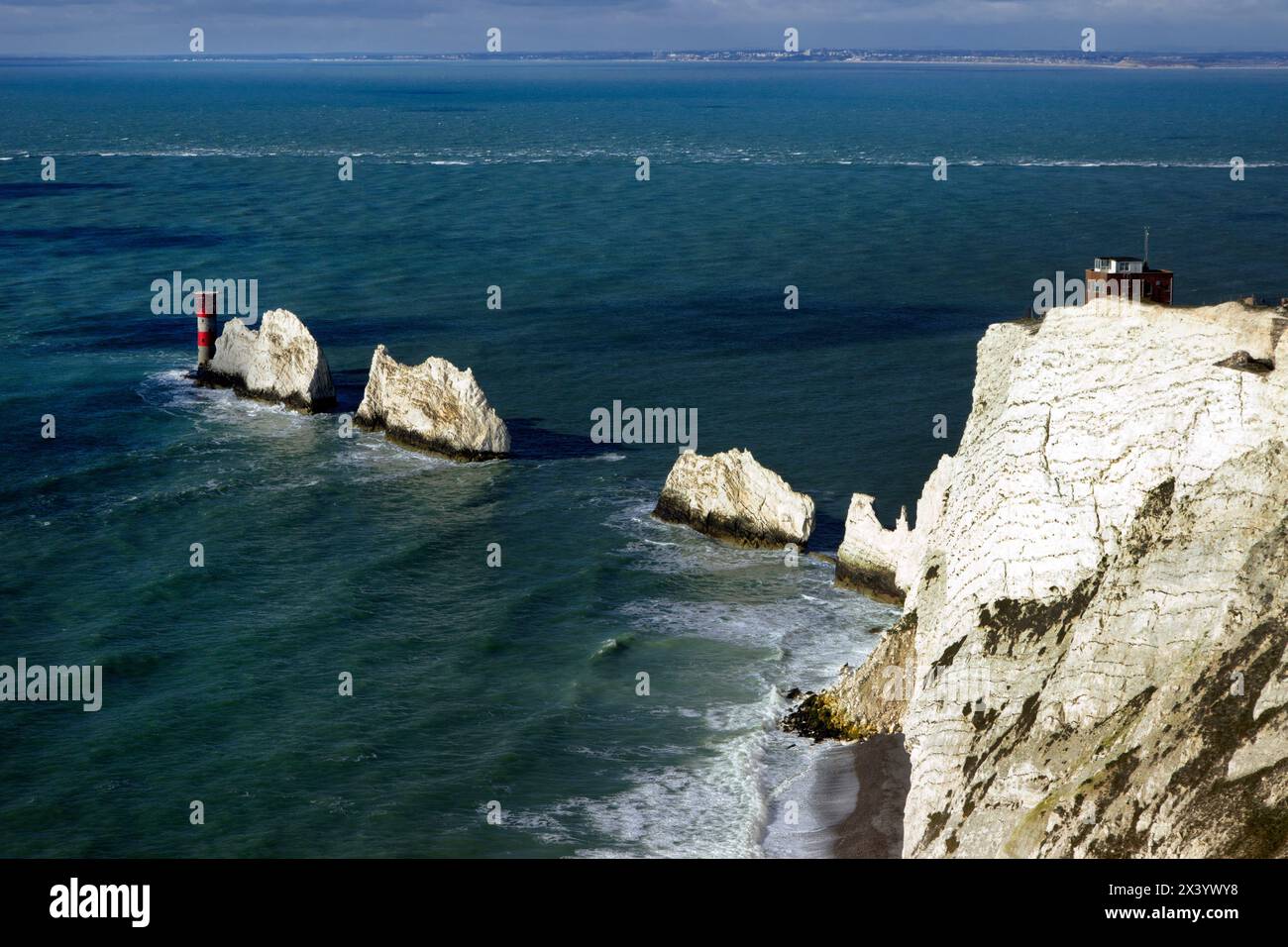 The Needles, eine Reihe von drei Kreidefeldern vor der Westküste der Isle of Wight, die etwa 30 m aus dem Meer ragt, mit dem Needles Lighthouse dahinter Stockfoto
