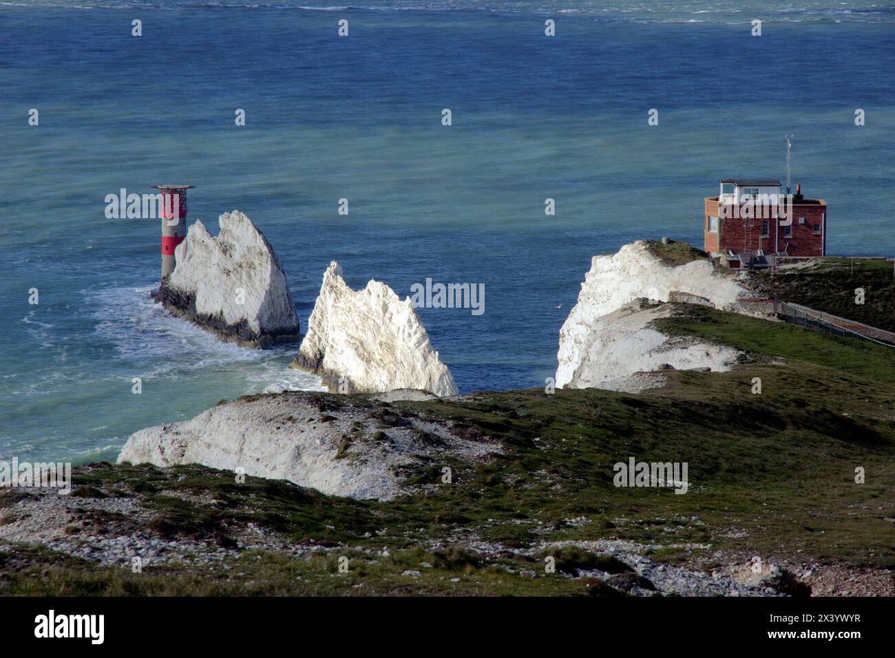 The Needles, eine Reihe von drei Kreidefeldern vor der Westküste der Isle of Wight, die etwa 30 m aus dem Meer ragt, mit dem Needles Lighthouse dahinter Stockfoto