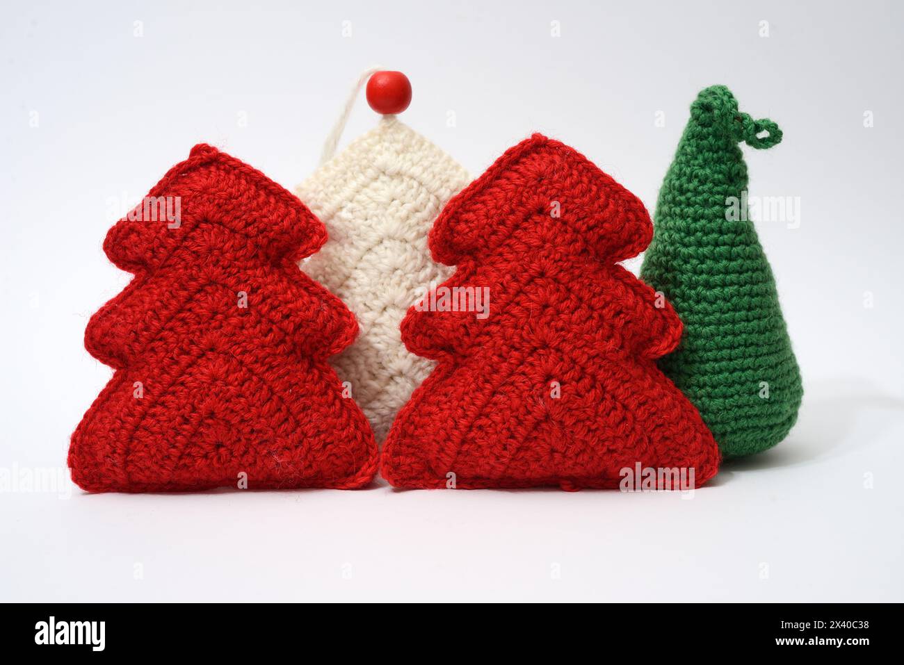 Lebendige Häkelbäume mit festlichen roten Ornamenten verleihen dieser handgemachten weihnachtsszene einen gemütlichen Charme Stockfoto
