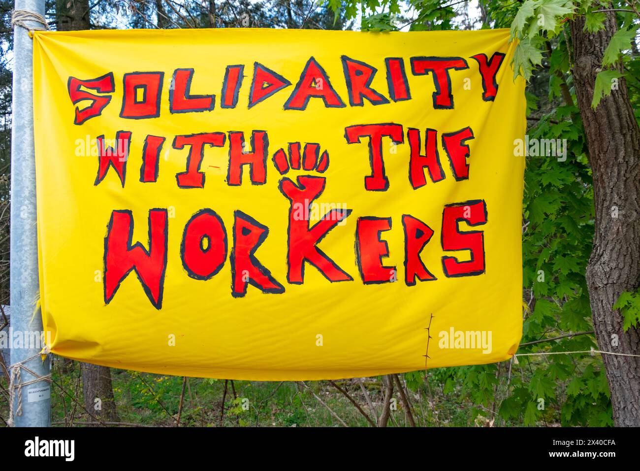 Auf dem Plakat der Demonstranten steht kühn ein Motto für Aktivisten, Solidarität mit den Arbeitern in roten Buchstaben auf gelbem Hintergrund, Hoffnung auf die Rechte der Arbeitnehmer Stockfoto