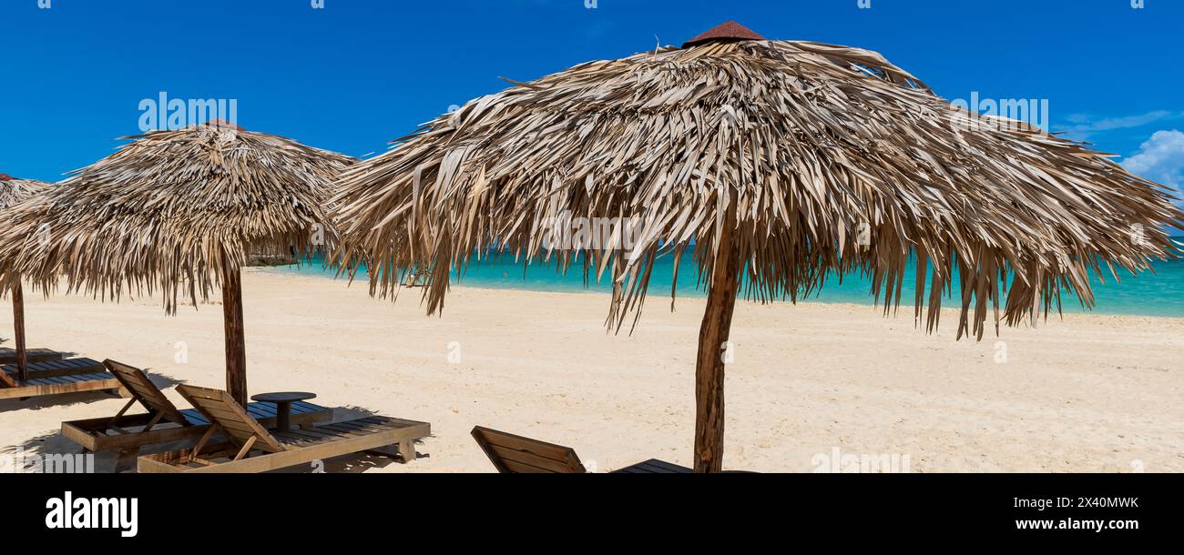 Sonnenliegen im Schatten am Strand Playa Pilar auf Cayo Guillermo im Jardines del Rey Archipel, mit klarem türkisfarbenem Wasser und Horizont im Jahr ... Stockfoto