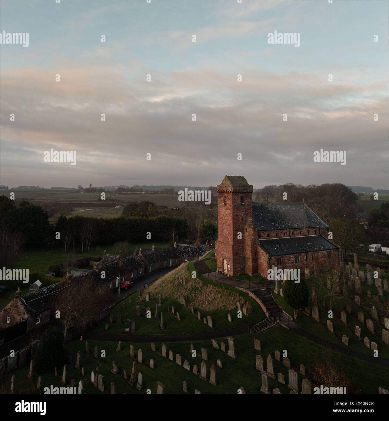 St. Vigeans Church aus der Vogelperspektive bei Sonnenuntergang, historische Pfarrei aus rotem Sandstein, umgeben von Friedhof und Landschaft, Angus, Schottland. Stockfoto