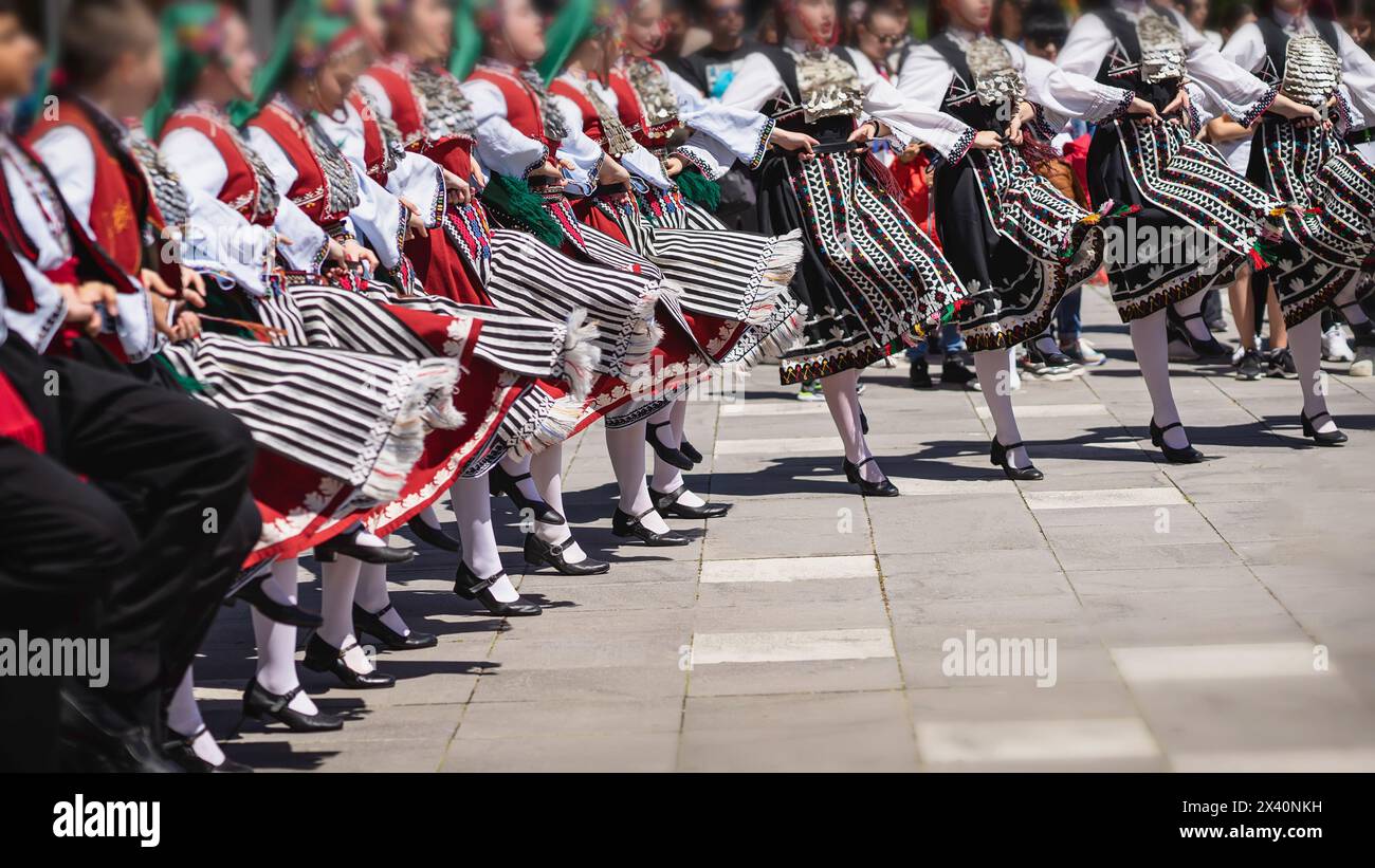 Bulgarische Tänzer in traditionellen Nationalkostümen tanzen fröhlichen Volkstanz im Freien Stockfoto