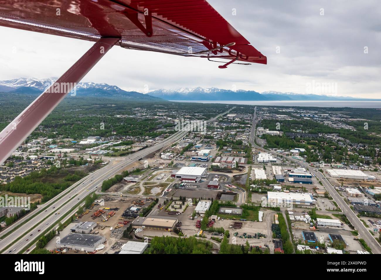 Blick auf die Stadt Anchorage von einem roten Wasserflugzeug an einem bewölkten Sommerabend; Anchorage, Alaska, Vereinigte Staaten von Amerika Stockfoto