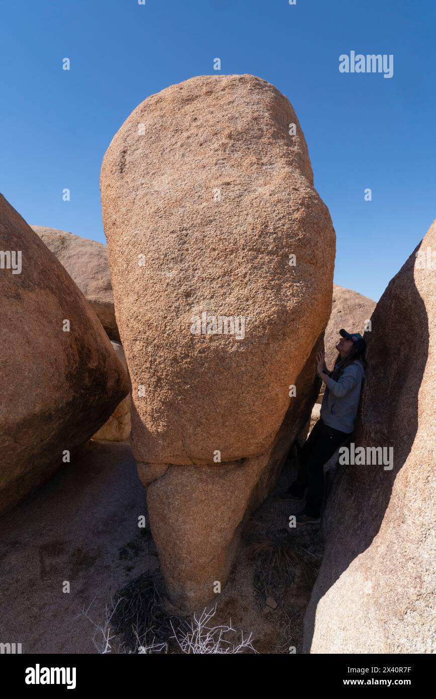 Frau, die an einer engen Stelle zwischen großen Felsen steht und die wunderschönen Felsformationen im Joshua Tree National Park erkundet Stockfoto