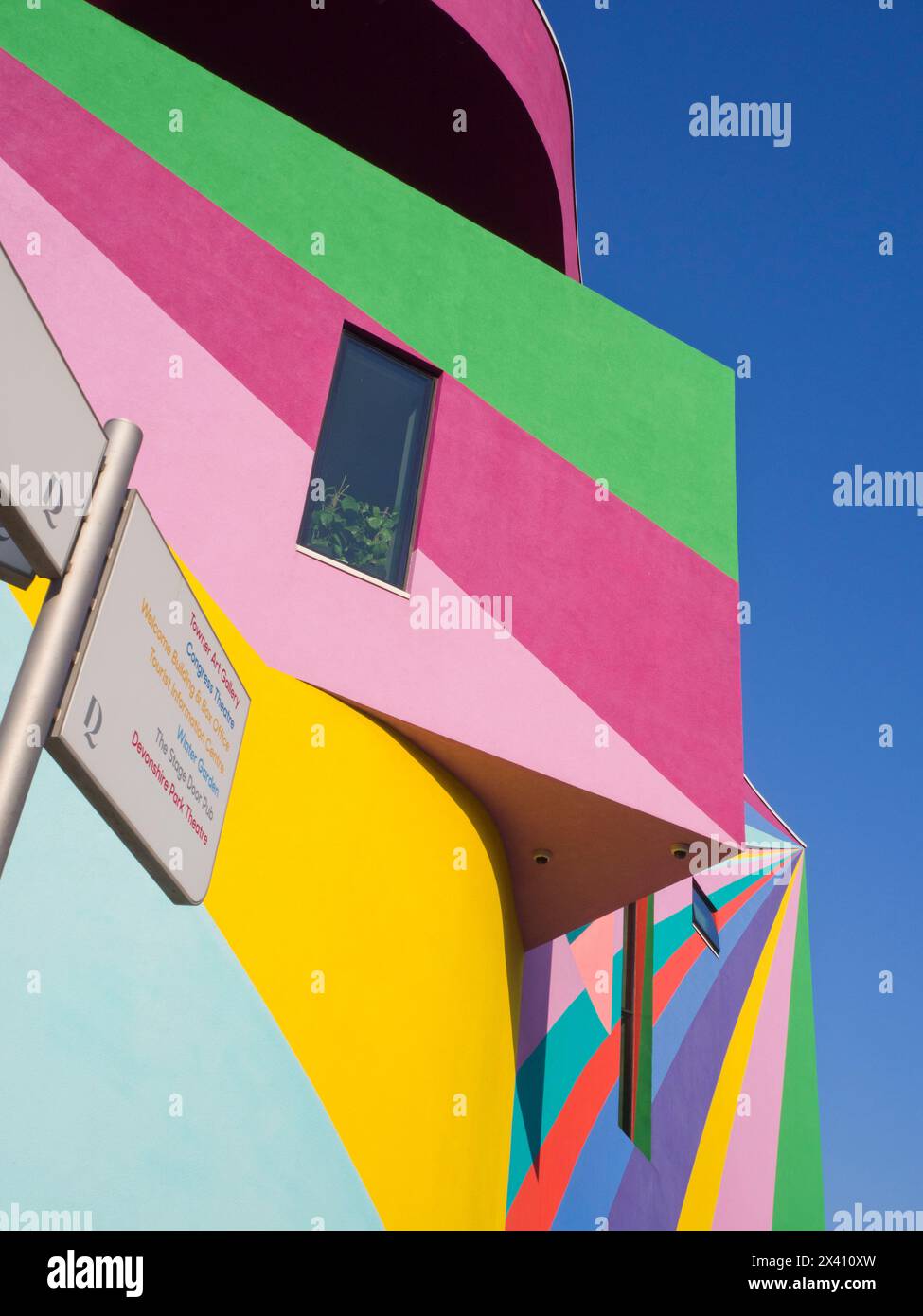 Außenwände einer Kunstgalerie in leuchtenden Farben vor blauem Himmel und Wegweiser mit einer Liste lokaler Sehenswürdigkeiten Stockfoto