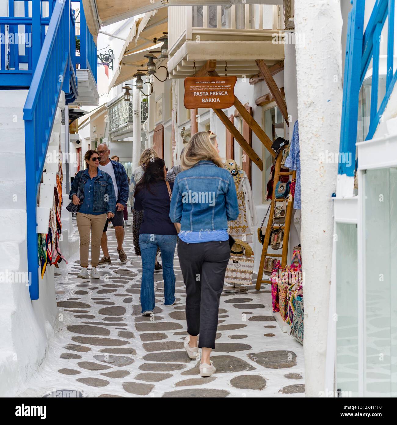 Typische Straßenszene auf der Insel Mykonos, mit Menschen, die auf einem schmalen Fußweg vorbei an Geschäften und Souvenirs schlendern; Mykonos, Griechenland Stockfoto