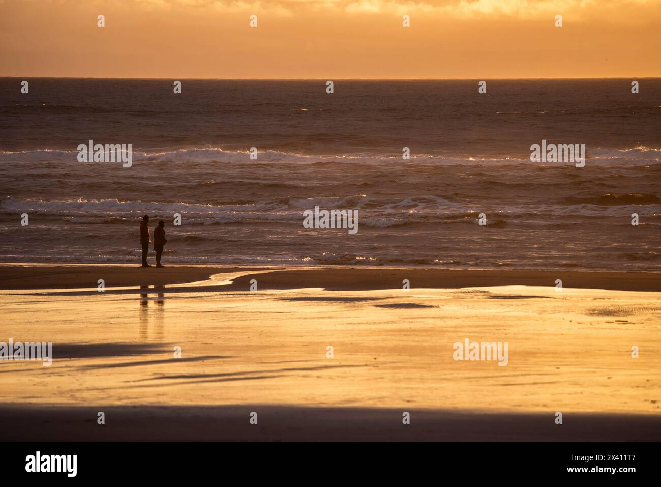 Paare beobachten den Sonnenuntergang über dem Pazifik vom Strand im Cape Disappointment State Park nahe der Mündung des Columbia River, Washington ... Stockfoto