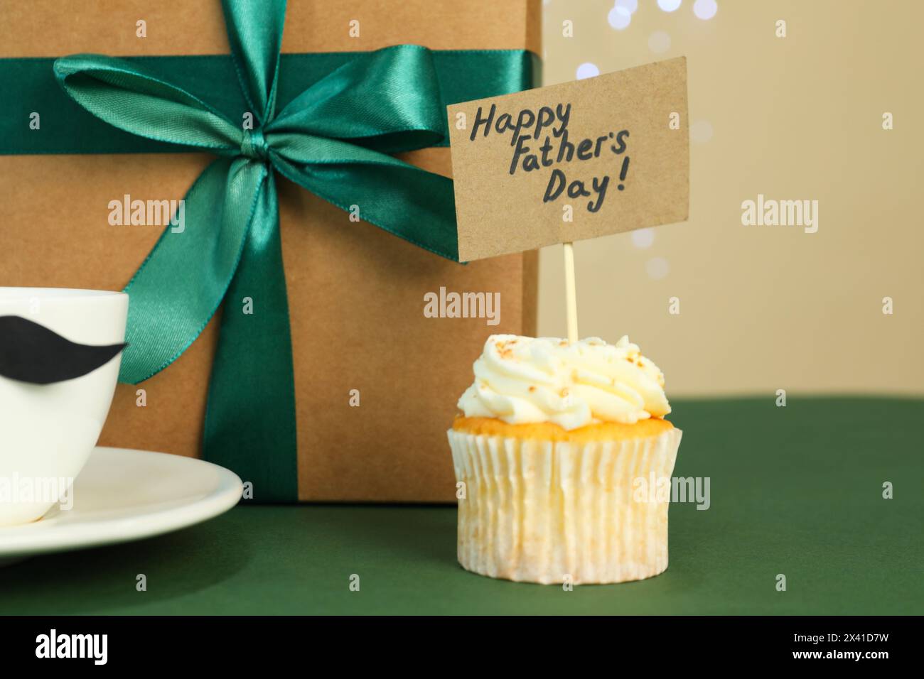 Alles Gute zum Vatertag. Leckerer Cupcake mit Grüßen und Geschenkbox auf grünem Tisch, Nahaufnahme Stockfoto