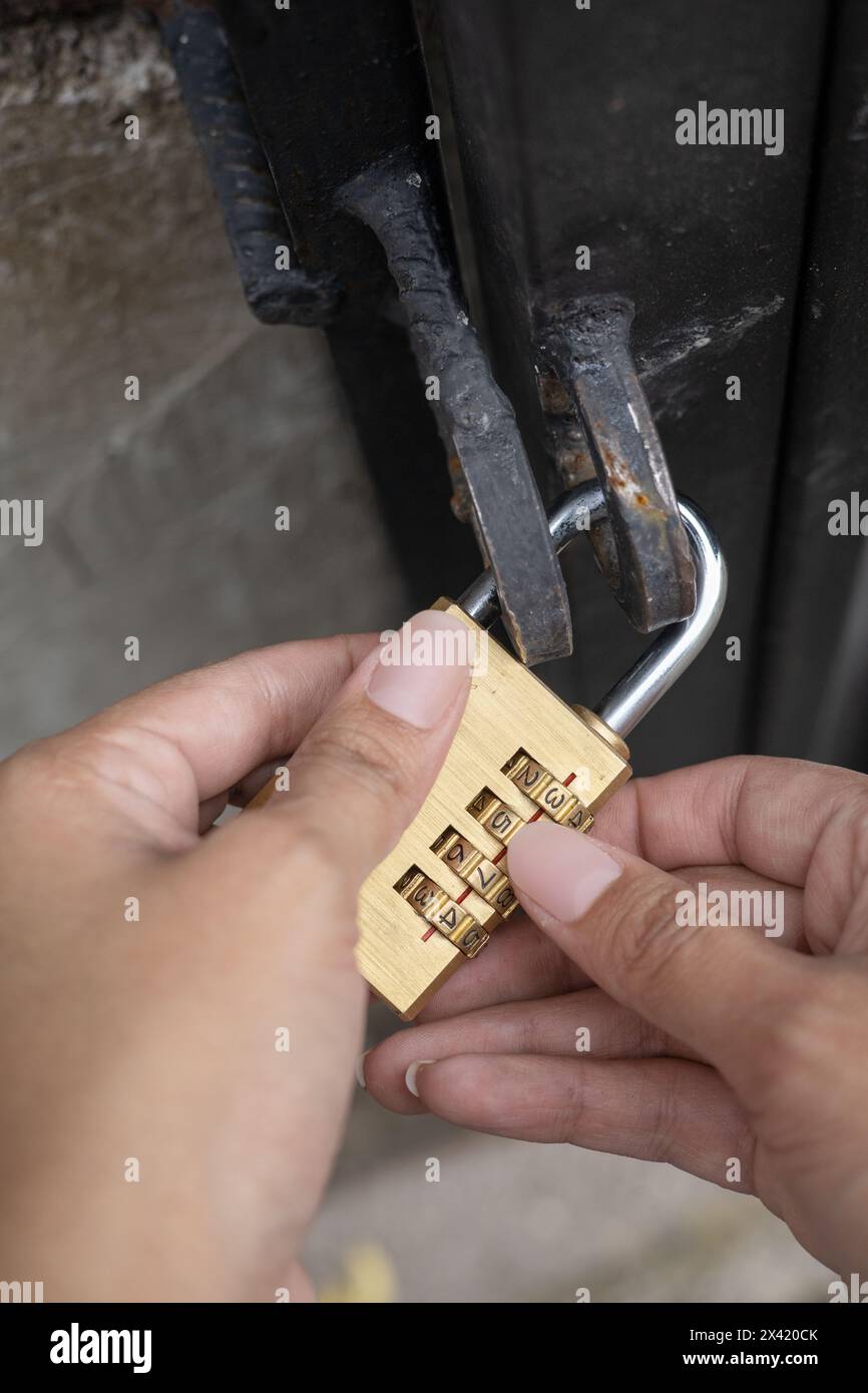 Vorhängeschloss mit Code, Hände einer Person, die den Schlüssel mit Zahlen platziert, Details zum Sicherheitsobjekt, Hintergrundbild Stockfoto