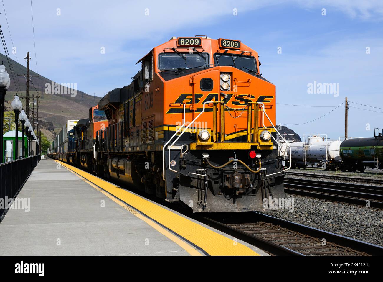 Wishram, WA, USA - 23. April 2024; Orange BNSF intermodaler Güterzug am Bahnsteig Whishram mit gelber Warnkante Stockfoto