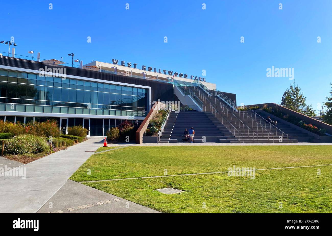 West Hollywood Park, West Hollywood, Los Angeles, Kalifornien. Leute sitzen auf den Stufen des West Hollywood Park Aquatic and Recreation Center. Stockfoto