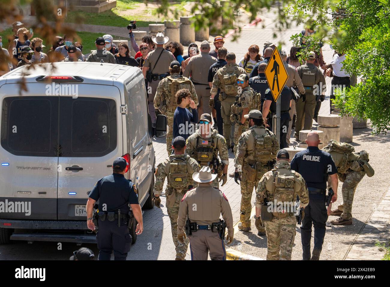 Austin, Texas, USA, 29. April 2024: Demonstranten stellen sich während einer pro-palästinensischen Kundgebung an der University of Texas in Austin gegen Polizeibeamte und einen Polizeiwagen. Der Campus wurde an einem dritten Tag in Folge von Demonstrationen erschüttert, als Dutzende Studenten und Unterstützer versuchten, eine Zeltstadt in der Nähe des Hauptverwaltungsgebäudes zu errichten. Texas State Troopers, Austin Polizei und UT Polizei verhafteten Dutzende von Menschen. Quelle: Bob Daemmrich/Alamy Live News Stockfoto