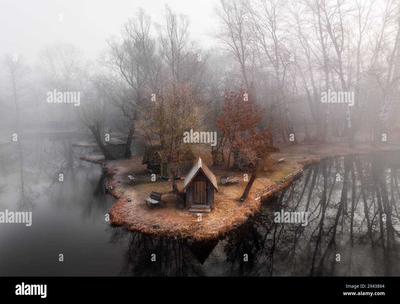 Szodliget, Ungarn - aus der Vogelperspektive eine traumhafte Winterszene am Szodliget Angelsee mit Fischerhütten und starkem Nebel an einem kalten Wintermorgen Stockfoto