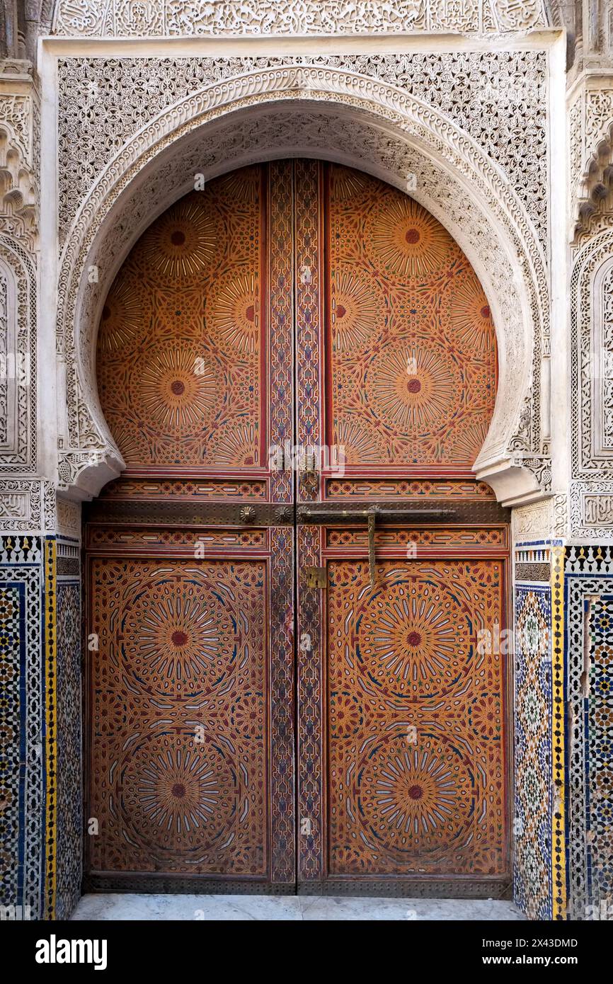 Fes, Marokko. Atemberaubende handgemalte Tür einer alten Moschee mit handgeschnitzten Putzarbeiten. Stockfoto