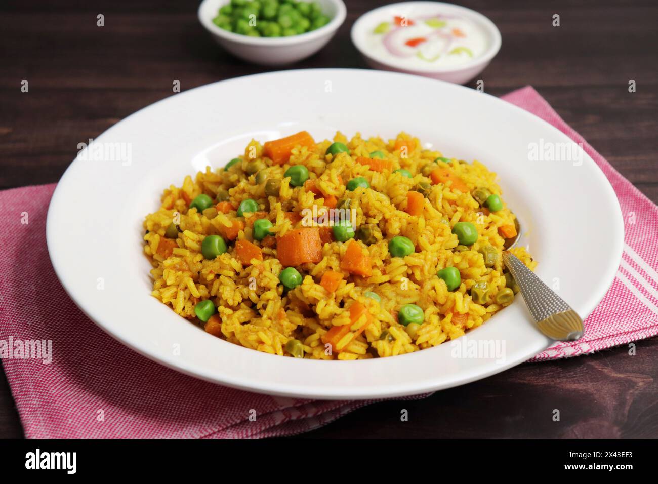 Karotten und Erbsen Pilaf oder Gajar Matar Pulao. Es ist ein eintöniges Reisgericht mit Basmati-Reis und Gemüse, gewürzt mit Gewürzen, serviert mit Joghurt Stockfoto