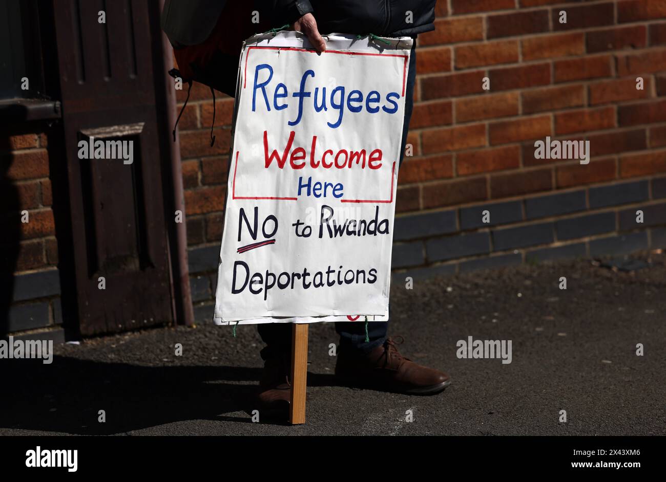 Loughborough, Leicestershire, Großbritannien. 30. April 2024. Ein Demonstrant, der gegen die geplante Deportation von Migranten und Flüchtlingen nach Ruanda demonstriert, steht vor einem Meldezentrum für Einwanderungsbehörden. Credit Darren Staples/Alamy Live News. Stockfoto