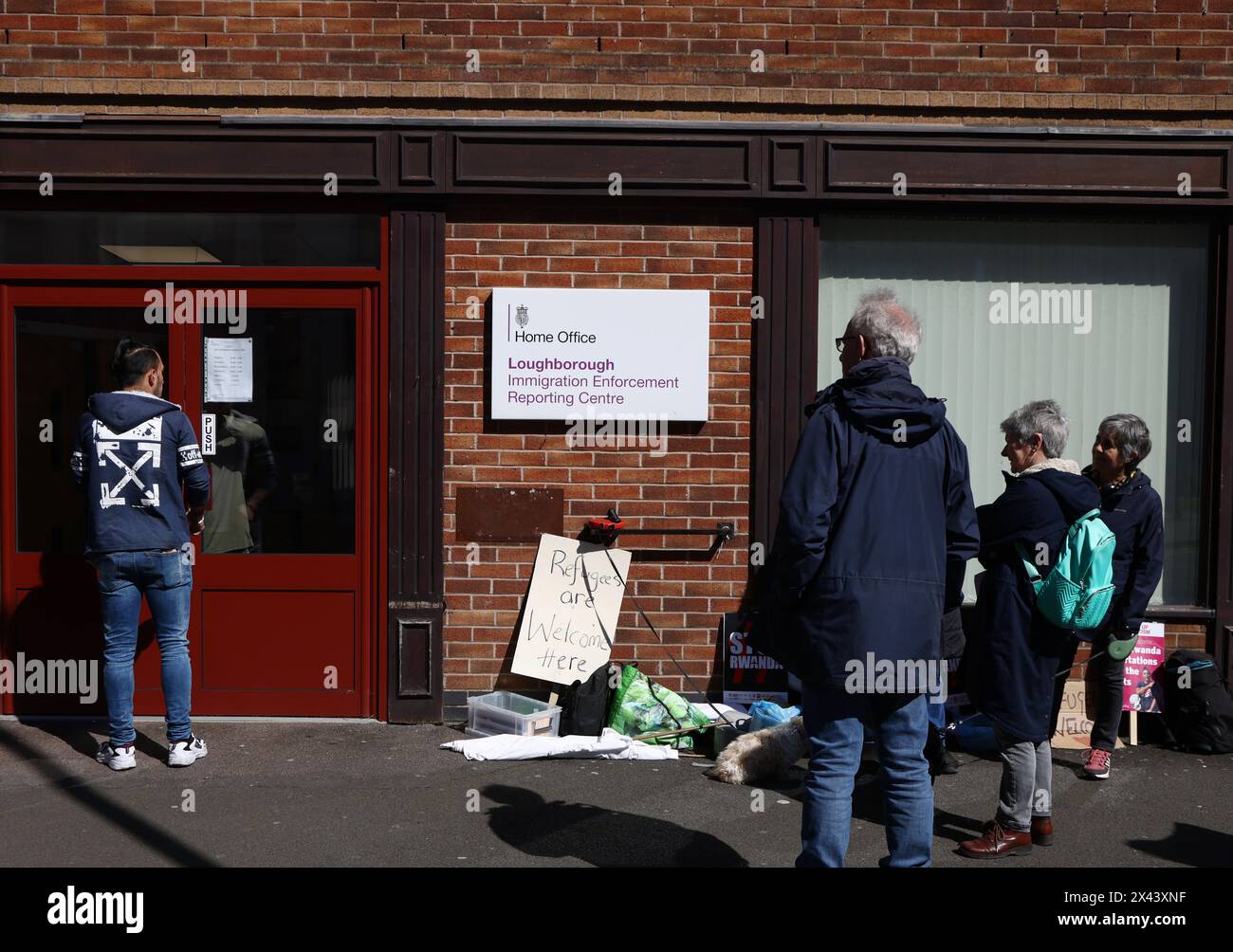 Loughborough, Leicestershire, Großbritannien. 30. April 2024. Ein Mann wartet auf den Eintritt in ein Meldezentrum für Einwanderungsbehörden, während Demonstranten gegen die geplante Deportation von Migranten und Flüchtlingen nach Ruanda protestieren. Credit Darren Staples/Alamy Live News. Stockfoto
