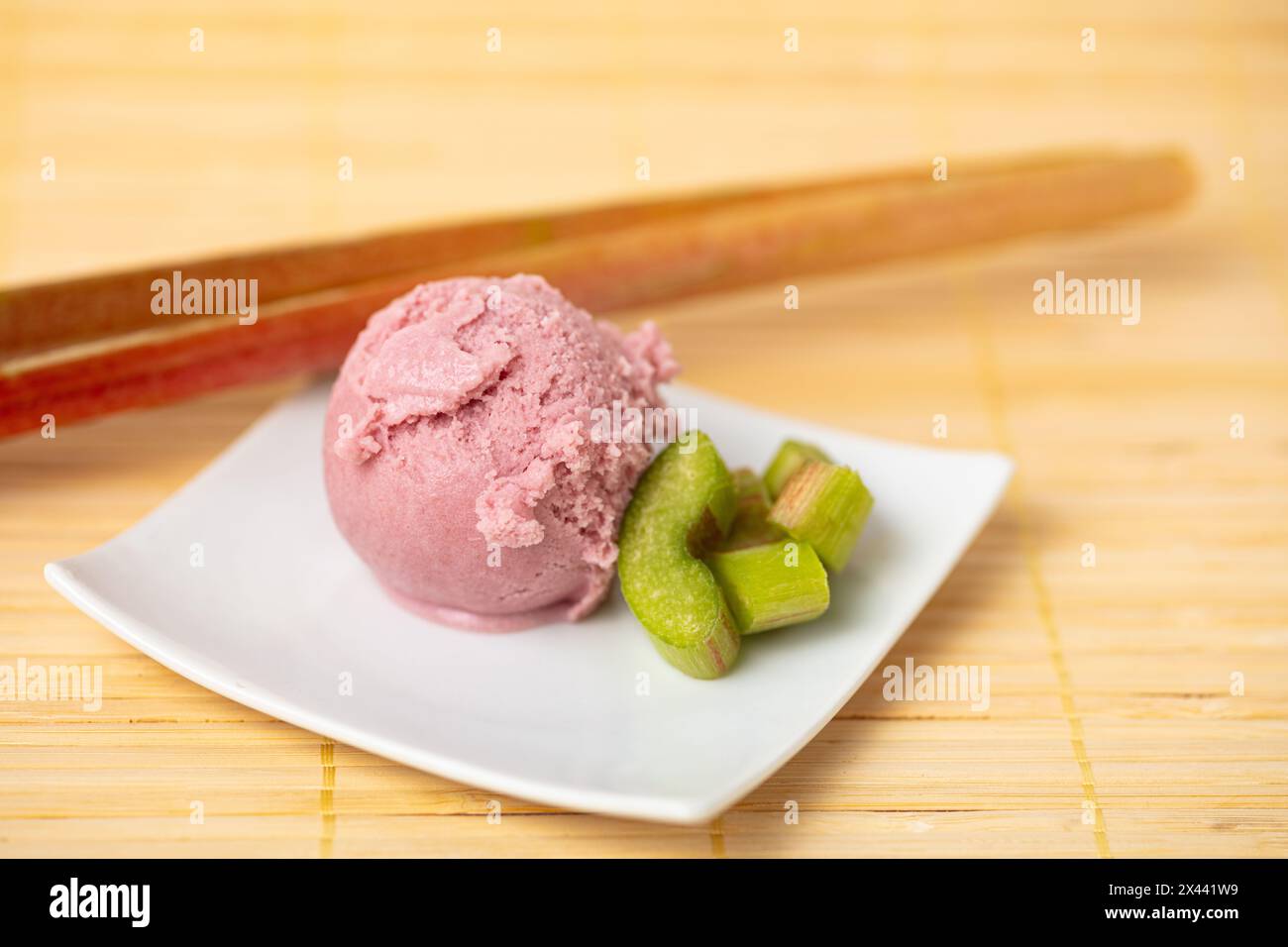 Frischer Rhabarber mit einer Kugel hausgemachtem Rhabarberreis auf einer Schüssel Stockfoto