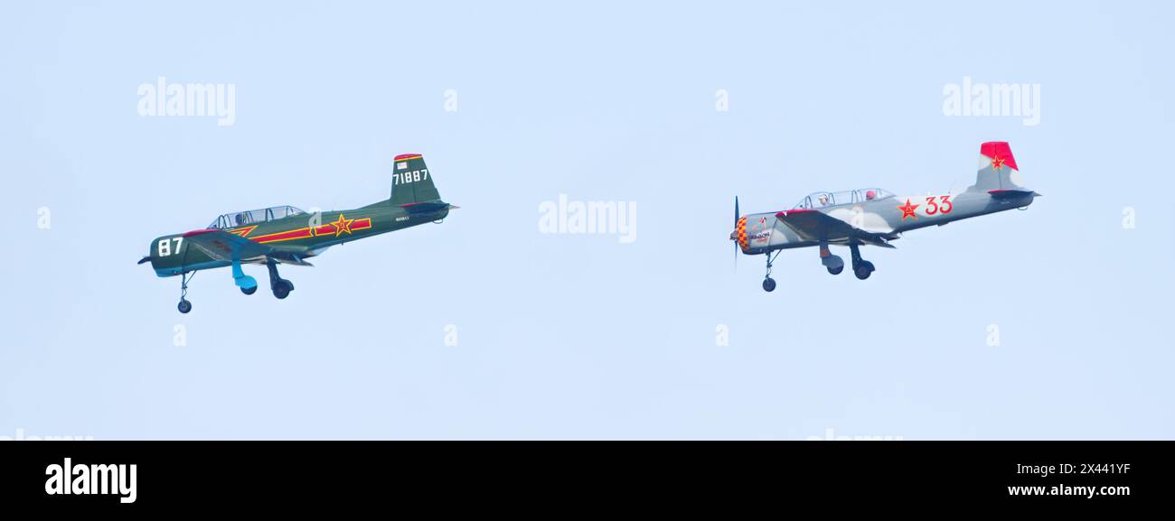 Zwei Privatflugzeuge, die sich bei einer Flugschau dicht verfolgen, Piloten sind isoliert auf hellblauem Himmel zu sehen Stockfoto