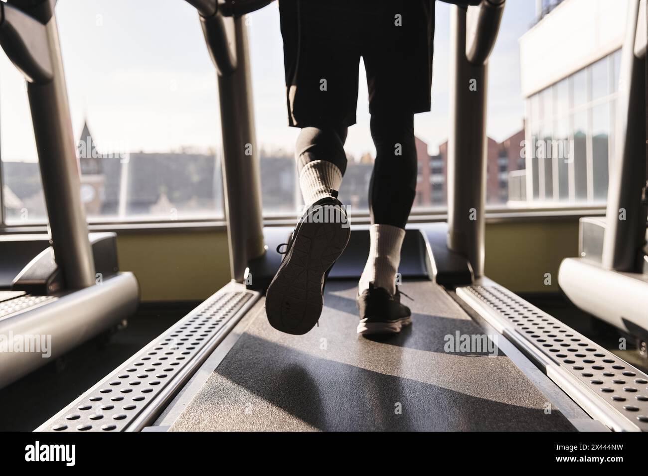 Ein sportlicher Mann in Aktivkleidung läuft im Fitnessstudio zügig auf einem Laufband und konzentriert sich dabei auf sein Workout. Stockfoto