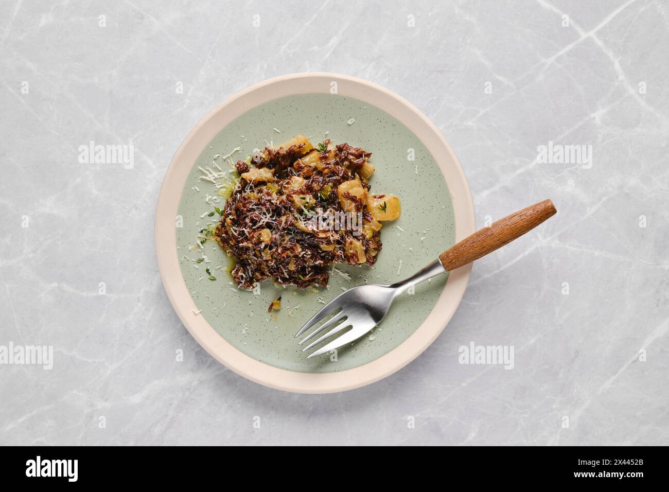 Teller mit Risotto mit rosafarbenem Reis, Birne und Blauschimmelkäse auf einem Tisch Stockfoto