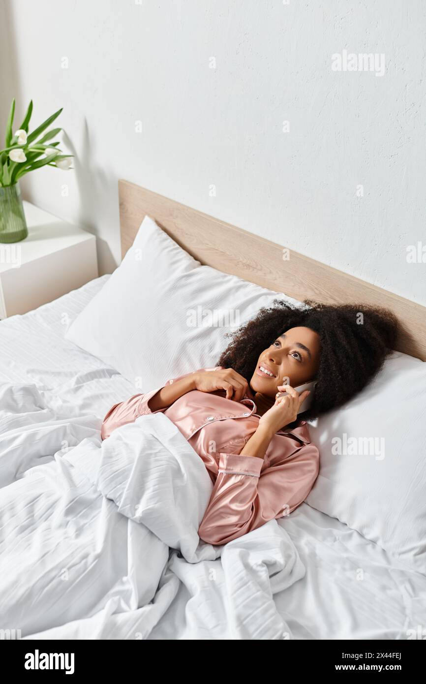 Eine Puppe liegt friedlich auf einem sauber gemachten Bett mit weißen Laken, was dem gemütlichen Schlafzimmerstil einen Hauch von Laune verleiht. Stockfoto