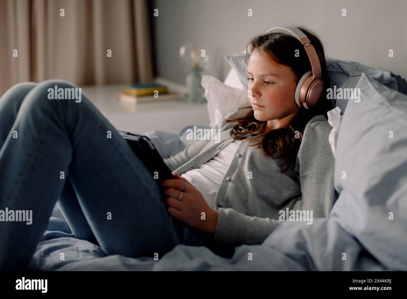Teenager Mädchen im Bett, das zu Hause Filme über ein digitales Tablet ansieht Stockfoto