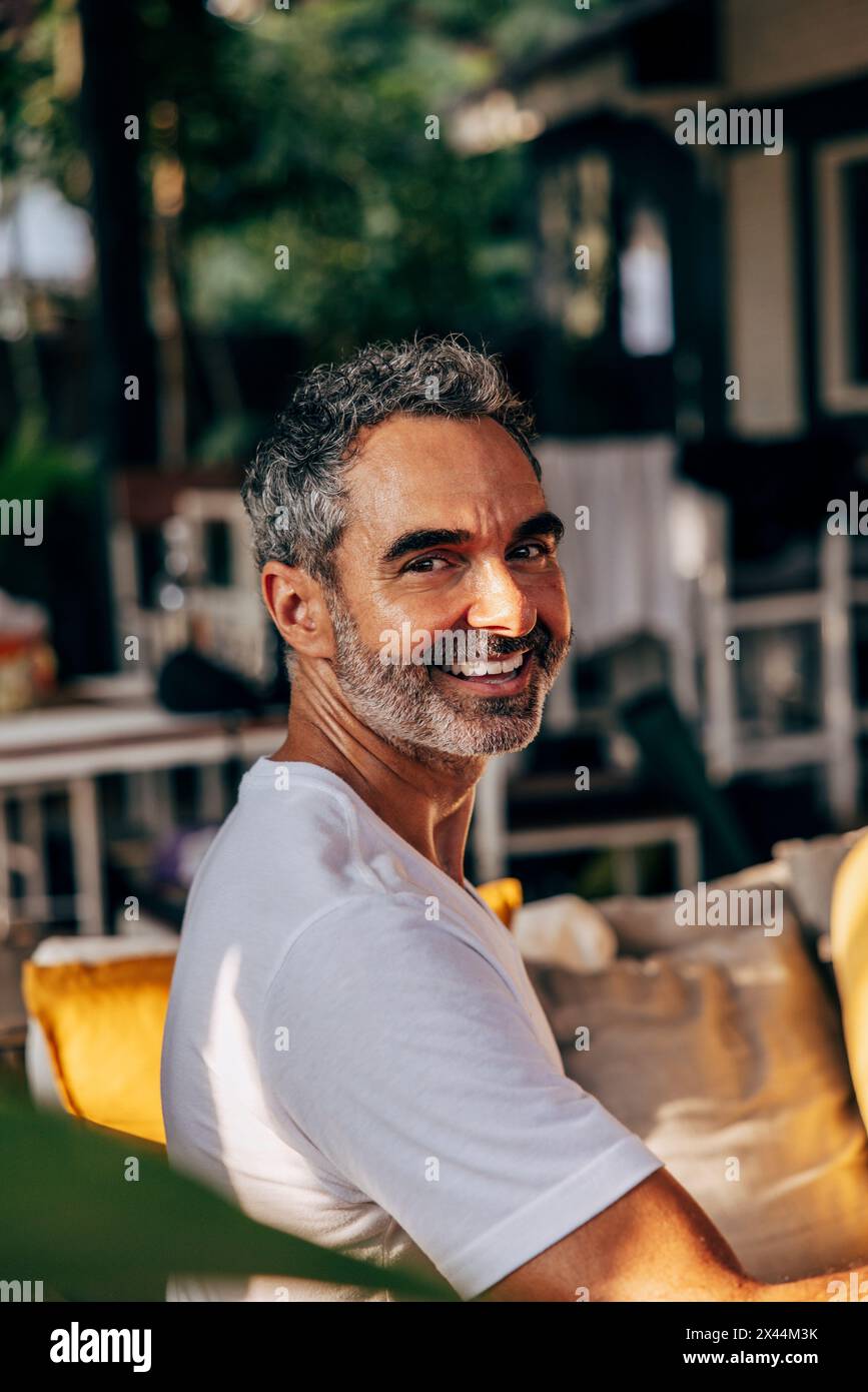 Seitenansicht eines lächelnden, reifen Mannes, der im Wellnessresort sitzt Stockfoto