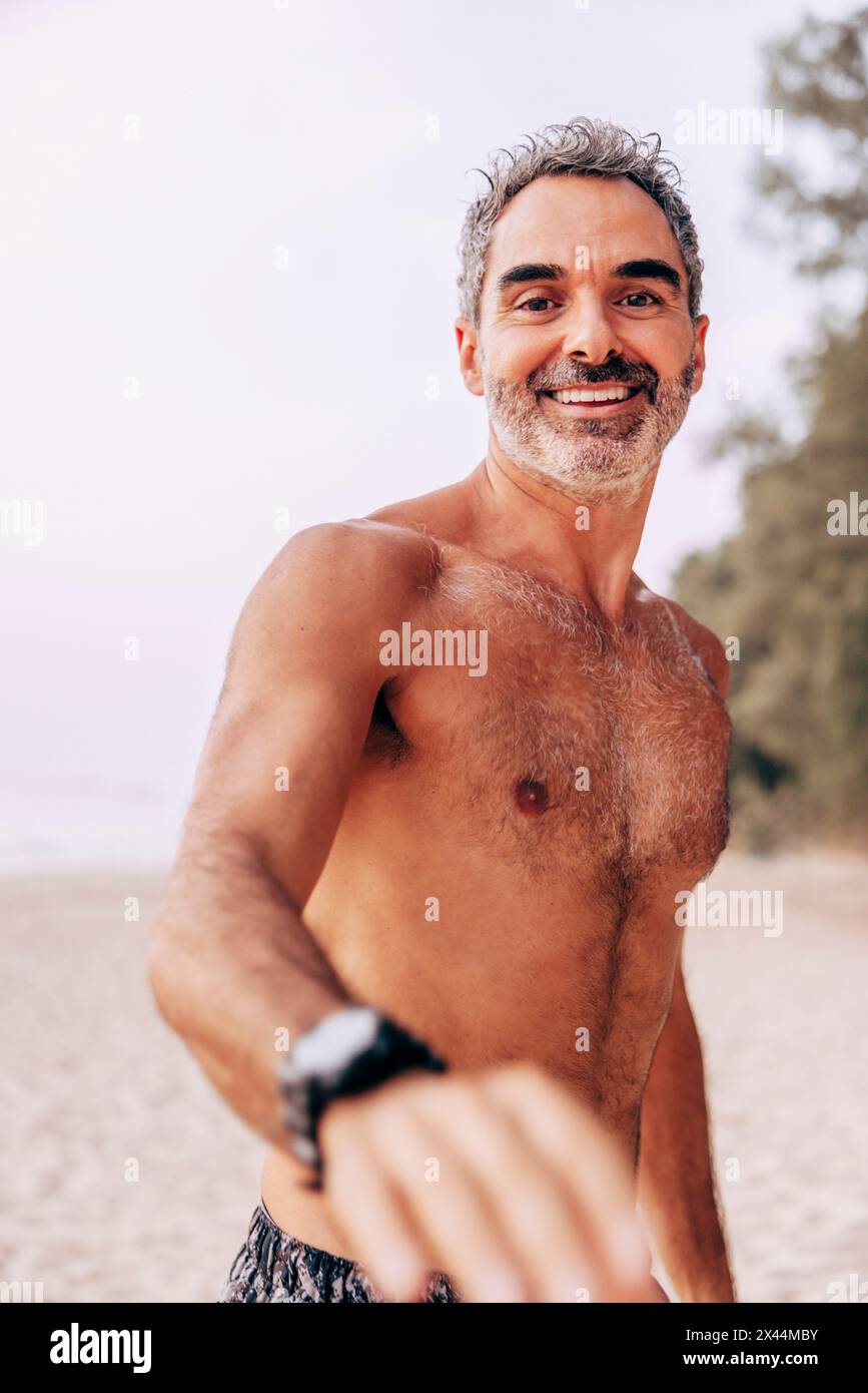 Porträt eines lächelnden Mannes ohne Hemd, der Urlaub am Strand verbringt Stockfoto