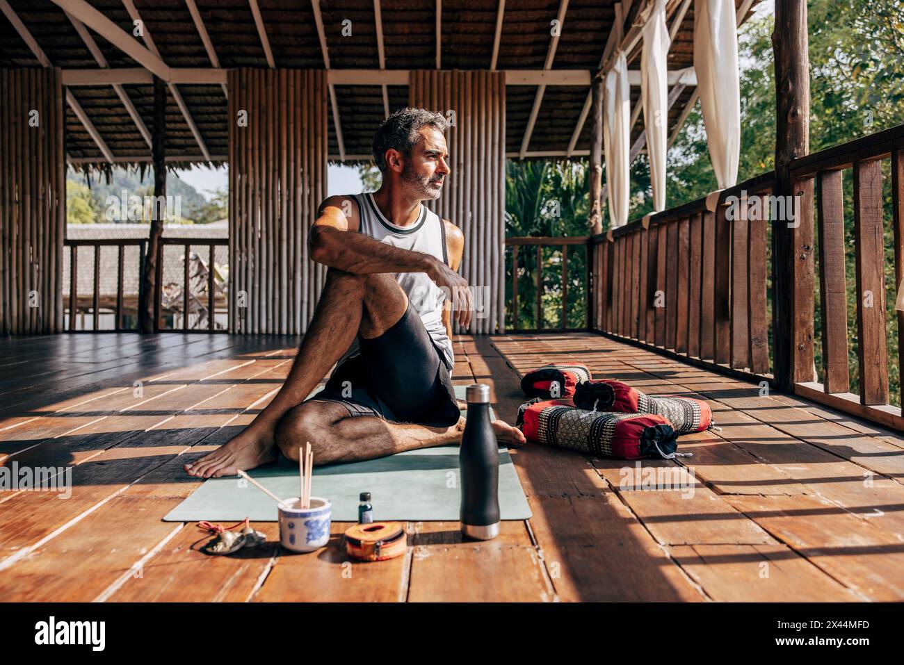 Reifer Mann, der Matsyendrasana auf Yogamatte im Wellnessresort spielt Stockfoto