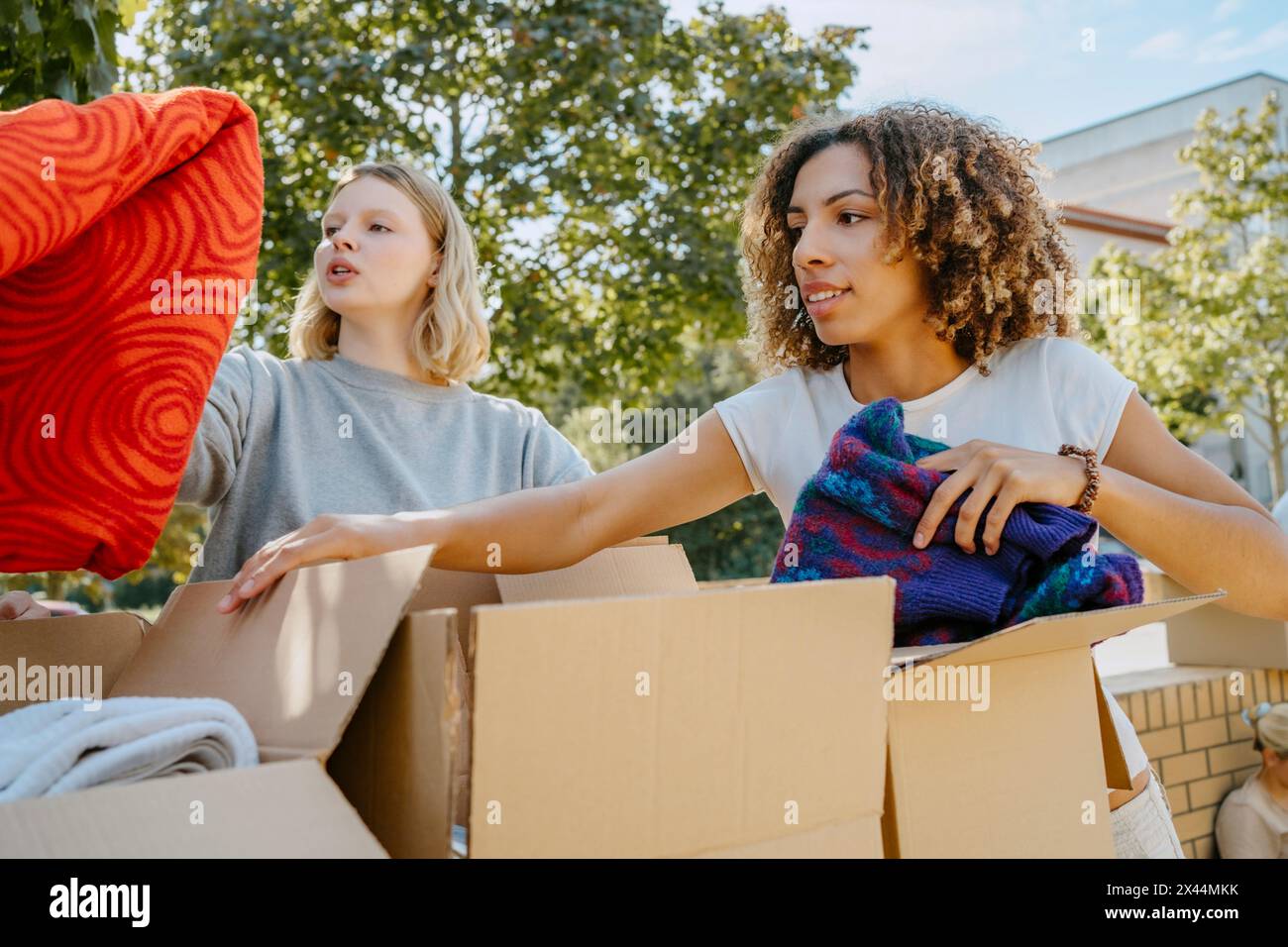 Gruppe von Freiwilligen aus verschiedenen Rassen sortieren Kleidung in Kartons im Gemeindezentrum Stockfoto