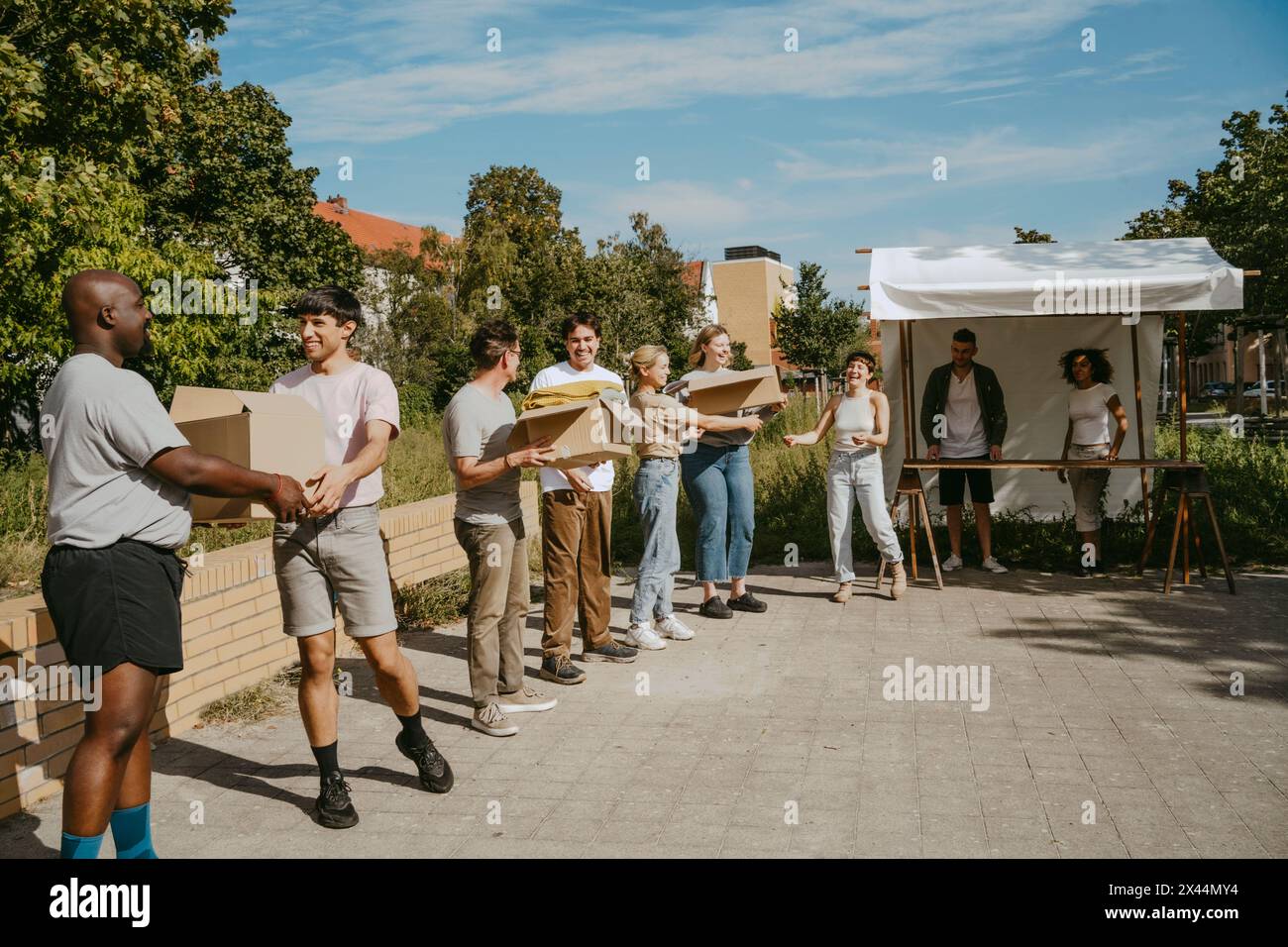 Gruppe von Freiwilligen, die während einer Wohltätigkeitsfahrt in der Gemeinde Spendenboxen übergeben, während sie in Reihe stehen Stockfoto