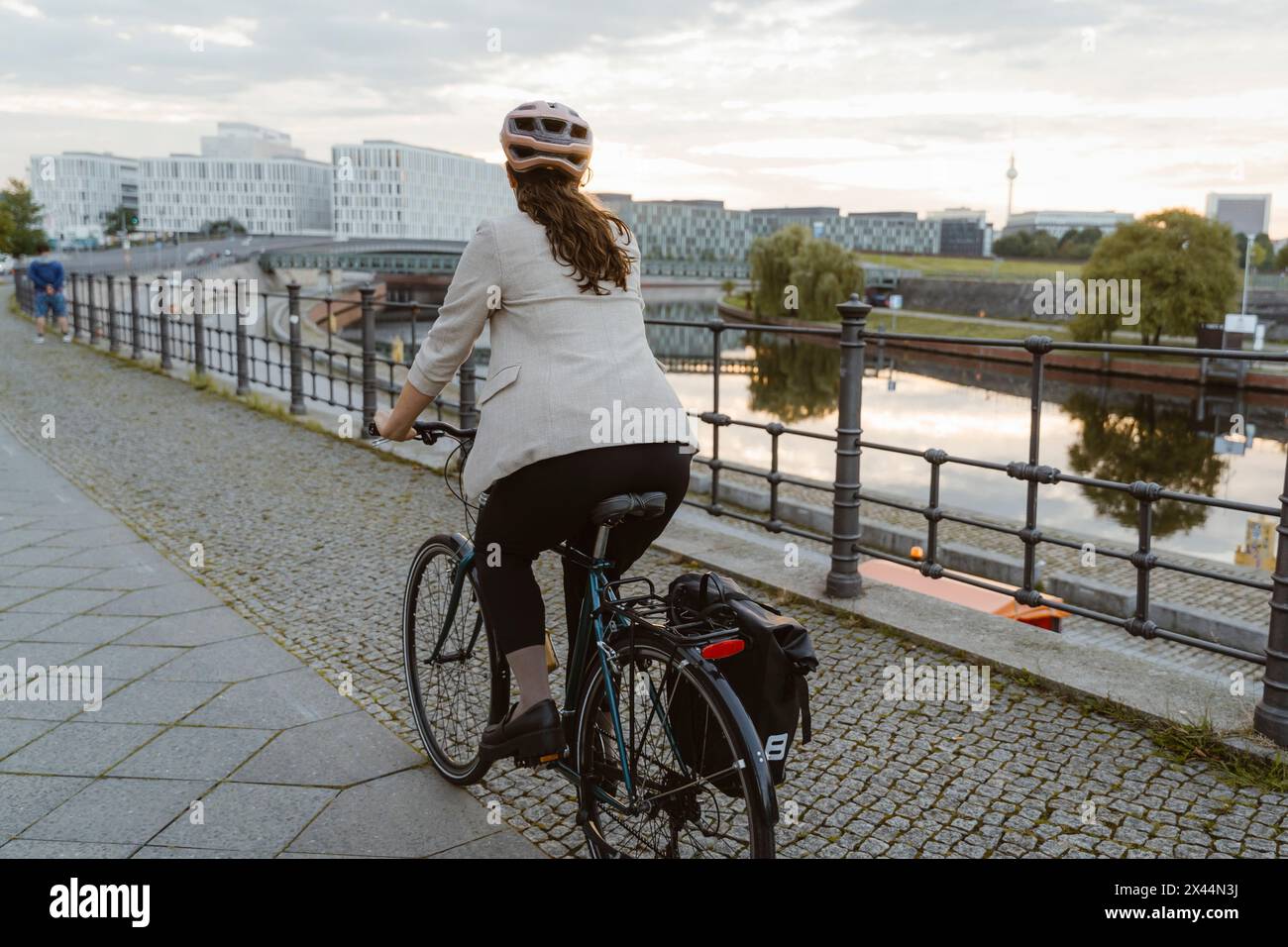 Rückansicht einer Geschäftsfrau, die auf der Promenade in der Stadt radelt Stockfoto