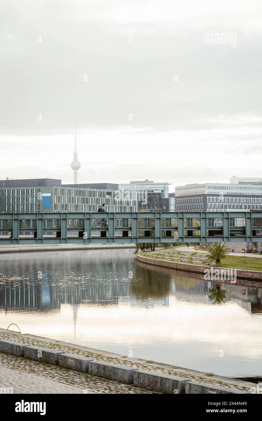 Geschäftsmann radelt auf der Brücke über den Kanal gegen den Himmel in der Stadt Stockfoto