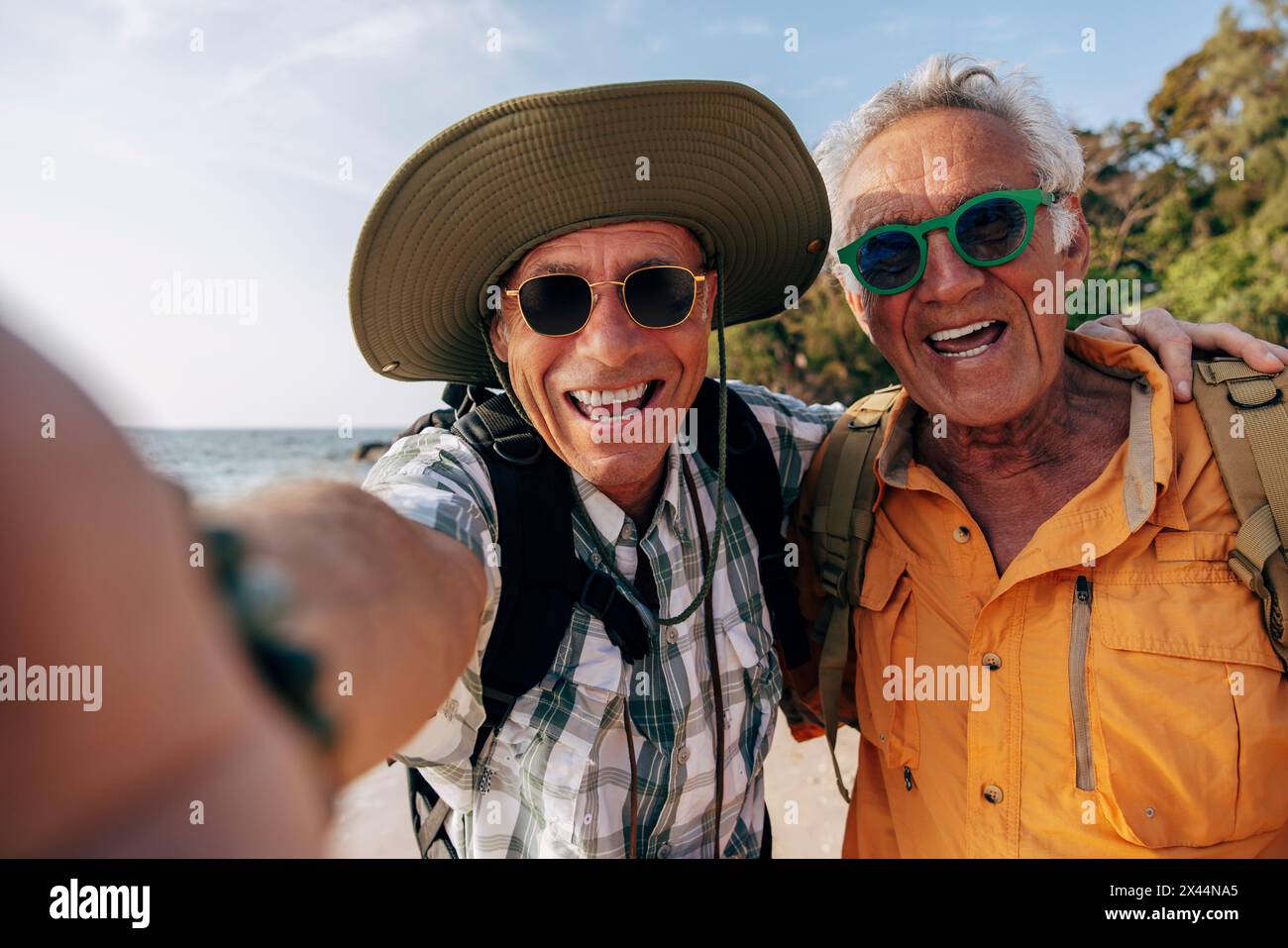 Porträt eines glücklichen älteren schwulen Paares, das Sonnenbrillen trägt und Selfie am Strand macht Stockfoto