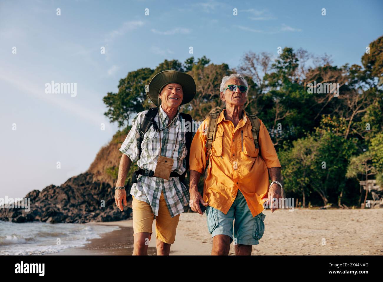 Ältere schwule Paare laufen zusammen am Strand im Urlaub Stockfoto