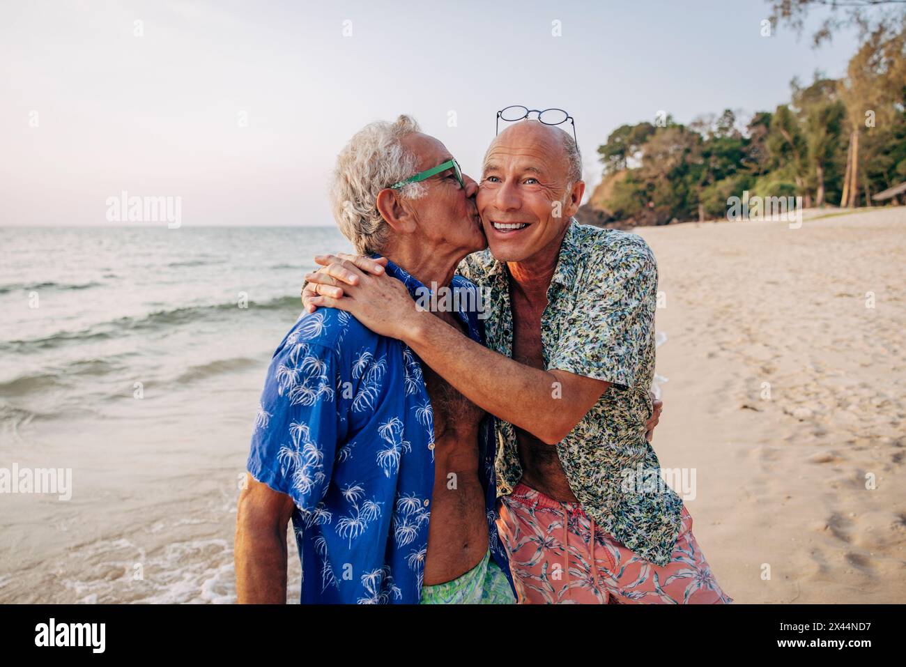 Ein älterer schwuler Mann küsst einen Freund im Urlaub am Strand Stockfoto