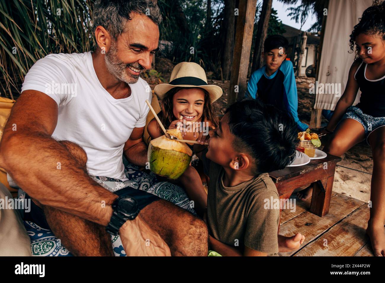 Kinder haben Spaß beim Trinken von Kokoswasser mit Vater im Urlaub Stockfoto