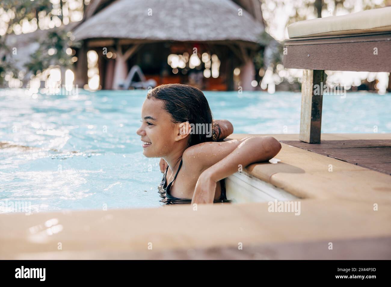 Lächelndes Mädchen, das beim Schwimmen im Pool im Resort eine Pause macht Stockfoto
