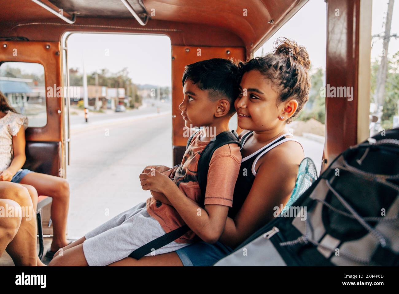Junge, der auf dem Schoß seiner Schwester sitzt, während er im Urlaub vom Tuk-Tuk reist Stockfoto