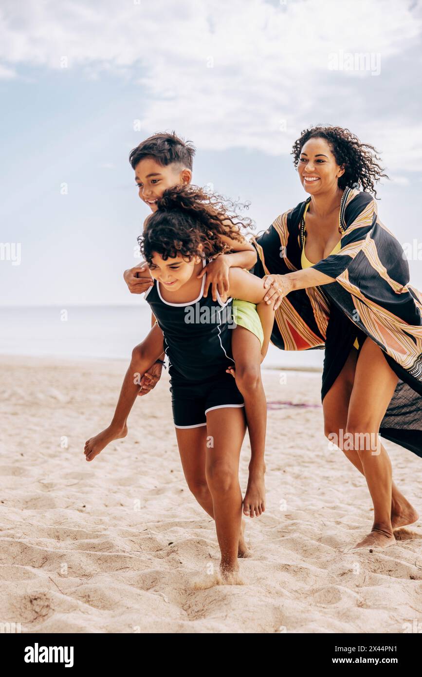 Mutter spielt mit Sohn und Tochter am Strand Stockfoto