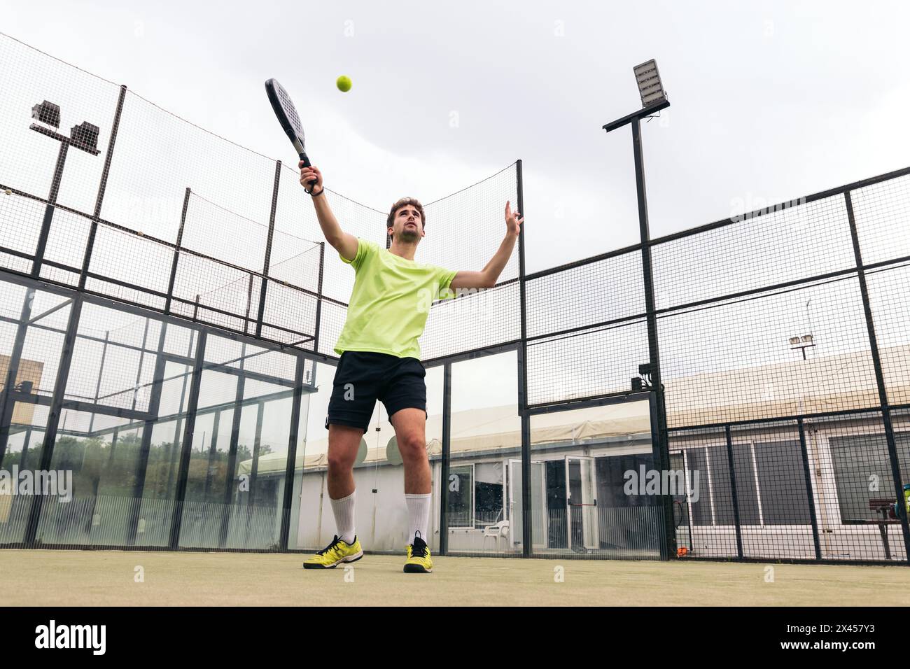 Junger Mann, der Paddle-Tennis spielt Stockfoto