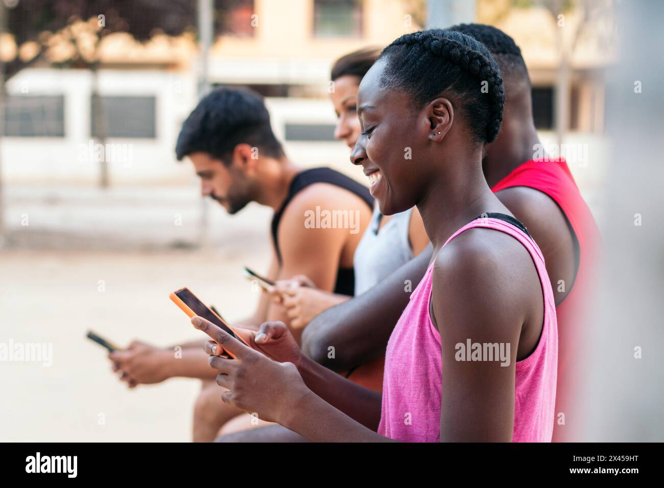 Gruppe multirassischer Freunde, die nach einem Basketballspiel ein Smartphone verwenden Stockfoto