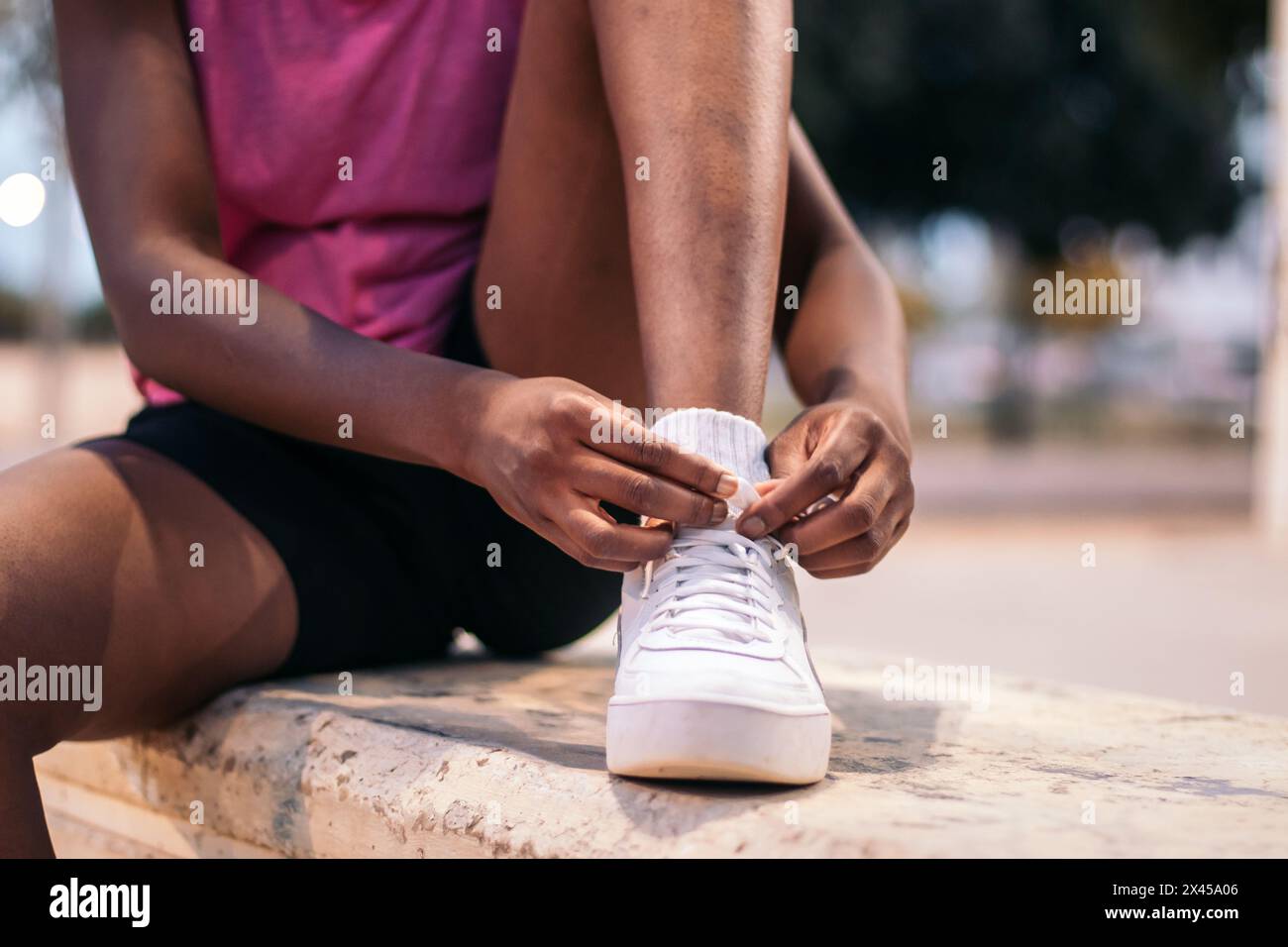 Unerkennbare schwarze Frau, die ihre Turnschuhe am späten Abend für Sport bindet Stockfoto