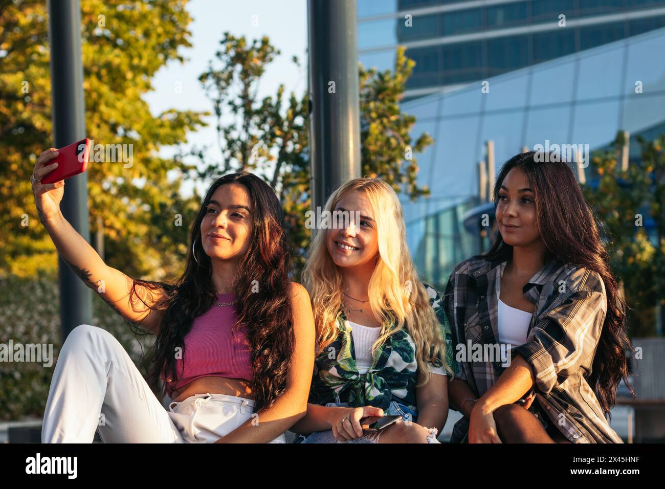 Drei Freunde hängen in der Stadt ab, machen Selfies mit dem Smartphone und haben Spaß Stockfoto