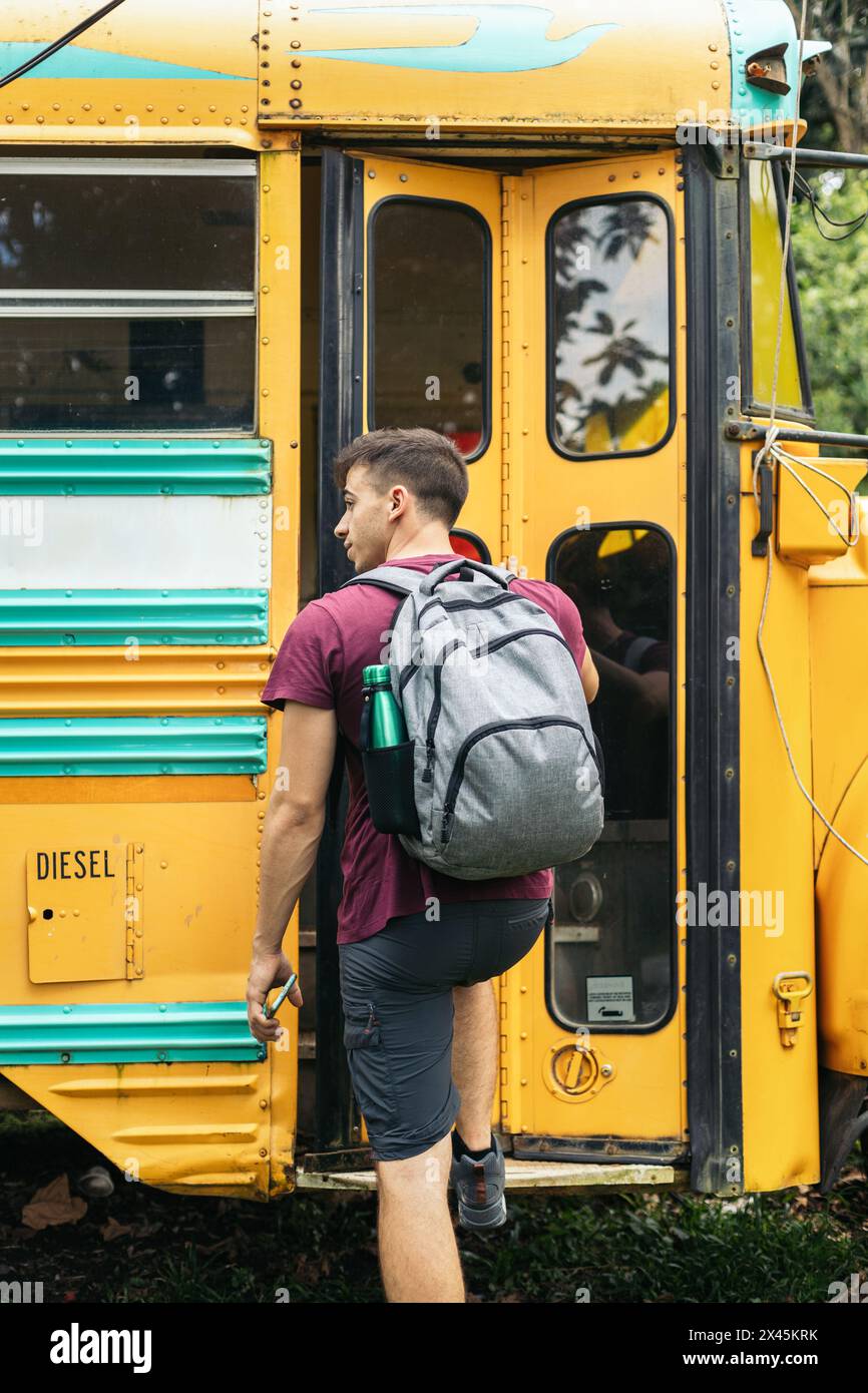 Rückansicht eines Jungen mit Rucksack, der in einen Schulbus fährt Stockfoto