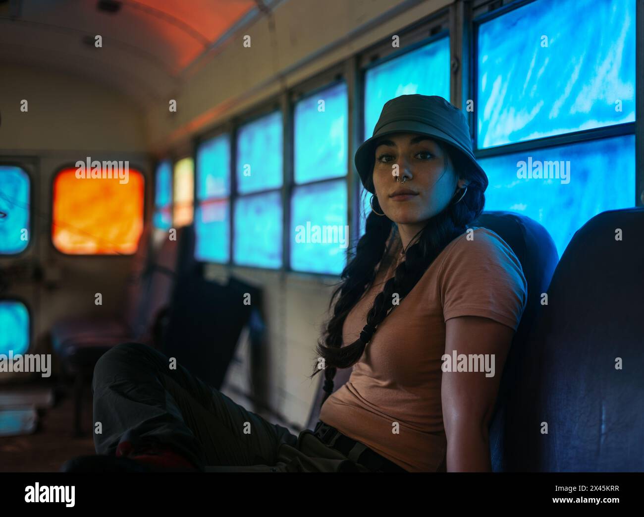 Frau sitzt in einem Retro-Bus mit blau getönten Fenstern Stockfoto
